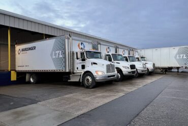 Four Hardinger LTL box trucks and one large LTL trailer lined up at loading dock.