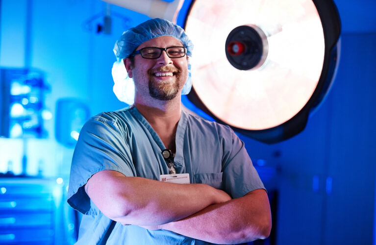 Doctors with hands crossed with surgery room in the background
