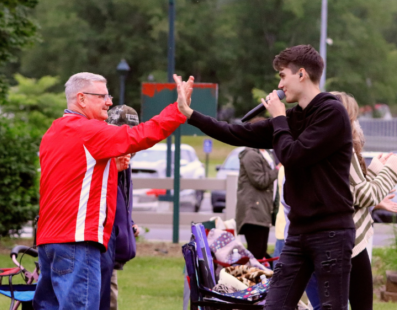 Father John Detisch, pastor of Saint Tobias Parish, high fives one of The Scally Brothers during their concert