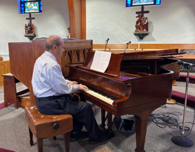 Stephen Toney, Queen of the World Parish Music Director, playing the piano repaired thanks to a Michael C. McCloskey Memorial Grant.