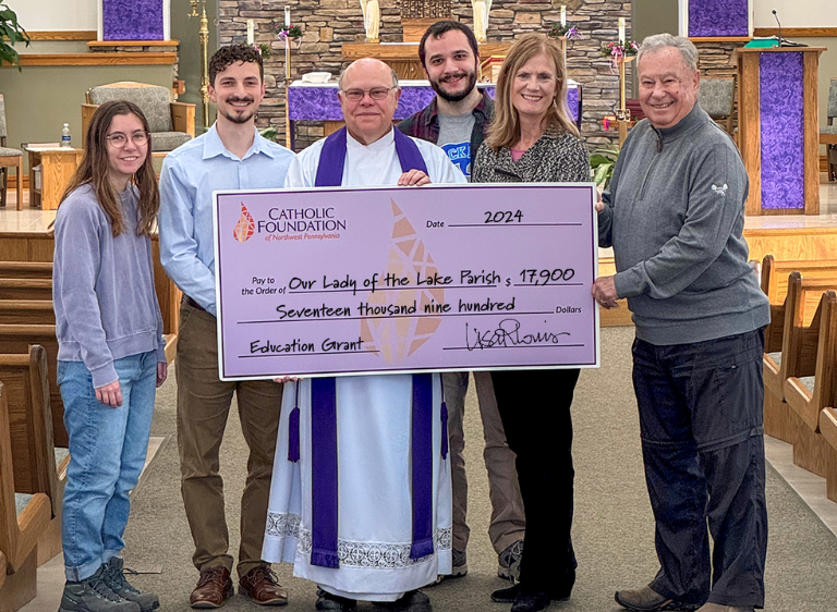 Bill Steger (Foundation Board Treasurer, right) and Lisa Louis (Executive Director) present grant check to Our Lady of the Lake Parish pastor Father Mark Hoffman and FOCUS missionaries who helped lead the SEEK conference: Piper Daleiden (left), Christian