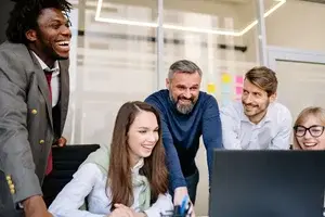 workers standing around a computer looking at a screen